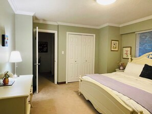 Un dormitorio con cama, mesita de noche, lámpara y una puerta que da a otra habitación.