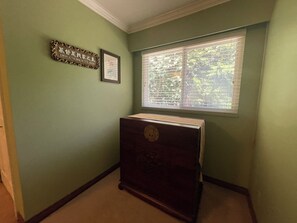 Ein Zimmer mit Fenster, einem gerahmten Schild und einem Holzkasten.