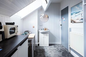 Une cuisine compacte équipée d’un four à micro-ondes, d’un évier et d’un miroir rond fixé au mur.