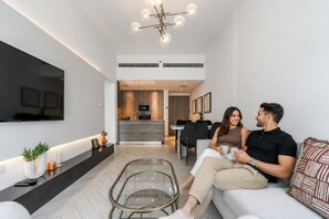 Ein modernes Wohnzimmer mit einer Couch, einem Glastisch und einem an der Wand befestigten Flachbildfernseher.