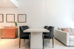 Ein zeitgemäßer Essbereich mit einem weißen Tisch, schwarzen Stühlen und einer Holzkabine.