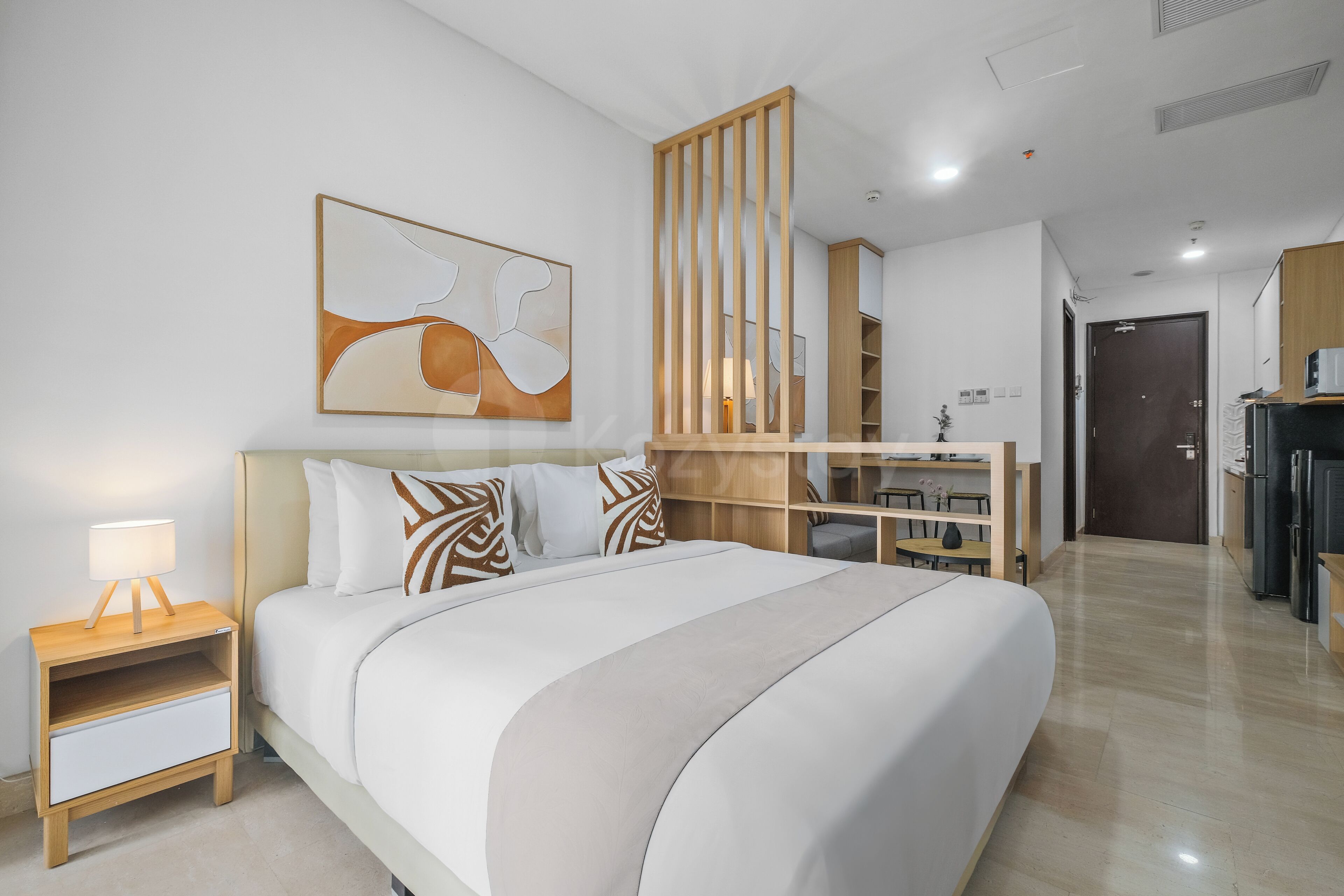 Ein modernes Hotelzimmer mit einem großen Bett, einem Nachttisch mit Lampe, einer Holzvertäfelung und einem Schreibtisch mit Stühlen.