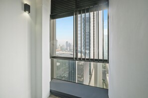 A room with a large window, a view of a cityscape, and a black metal railing. - Harumi by Kozystay - Sudirman (Central Jakarta)