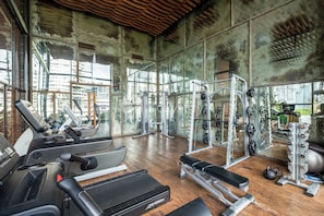 A gym with treadmills, weight machines, and a bench. - Harumi by Kozystay - Sudirman (Central Jakarta)