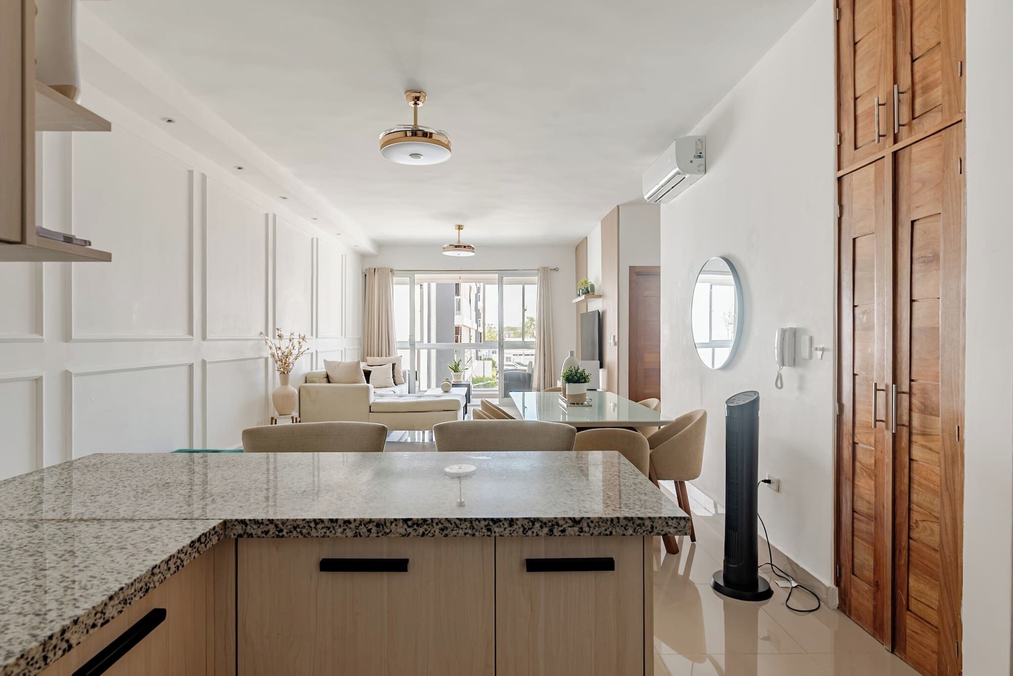 A modern kitchen with a granite countertop, wooden cabinets, and a dining area with a table and chairs.