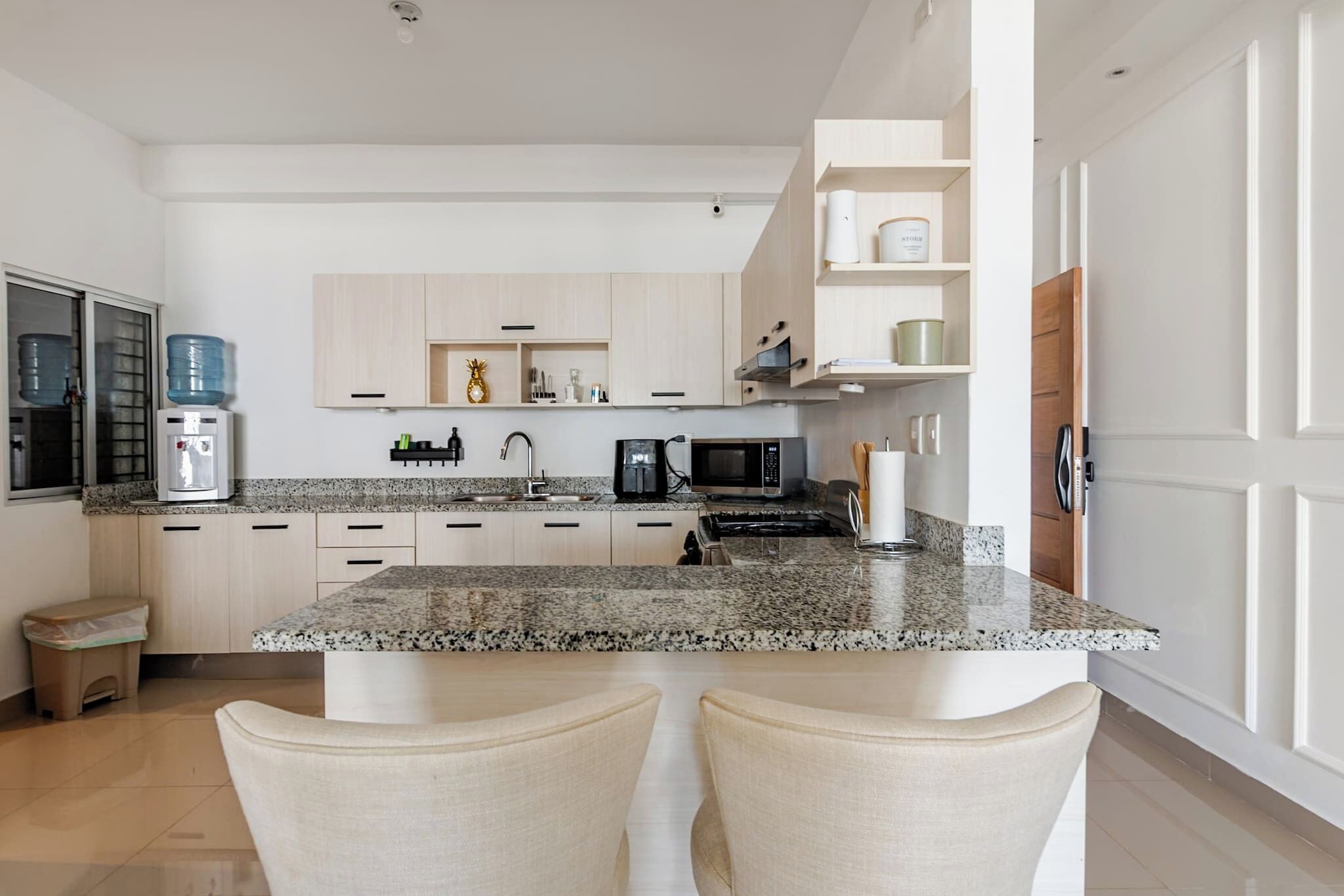 Eine moderne Küche mit Granit Arbeitsplatten, Edelstahlgeräten und hellen Holzschränken.