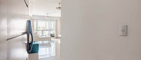 A hallway with a white wall, a door, and a light switch.