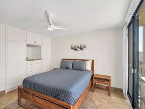 A bedroom with a bed, wooden headboard, bedside table, and a ceiling fan. - 3B/2B Seavista Beach Front Great View (South Padre Island)
