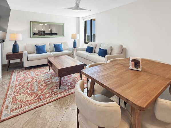 Uma sala de estar moderna com um conjunto de sofás, uma mesa de centro de madeira e uma mesa de jantar com cadeiras.