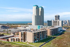 A high-rise building with multiple floors, surrounded by other buildings, and a view of the ocean in the background. - 3B/2B Seavista Beach Front Great View (South Padre Island)