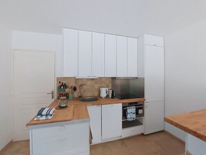 A compact kitchen with white cabinets, a wooden countertop, a sink, a kettle, and a refrigerator. - Les Sources by Interhome (Draguignan)