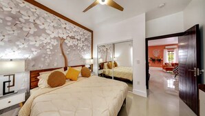 Una camera da letto con un letto grande, una ventola a soffitto, un muro con un motivo alberi e uno specchio.