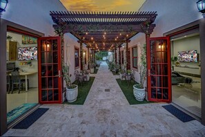 A covered outdoor corridor with a central pathway, potted plants, and a seating area. - Romantic 2Bed/2Bath/2K - 5★ DT Location -♛Hot Tub (Fort Lauderdale)