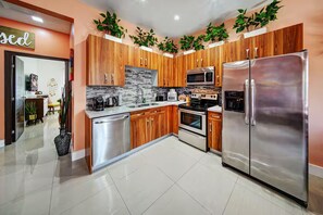 Cocina moderna con armarios de madera, electrodomésticos de acero inoxidable y piso de baldosas.
