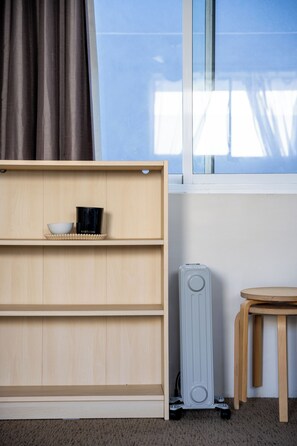 Ein Zimmer mit Holzregal, Heizkörper und einem fenster mit Vorhängen.
