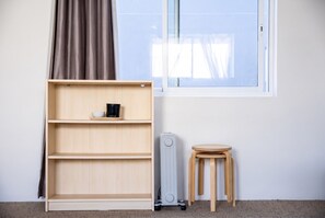 A room with a wooden bookshelf, a small wooden stool, and a radiator. - Bondi Beach Studio | 2 Min Walk to Beach, Sleeps 4, Work-From-Beach Desk (Bondi Beach)