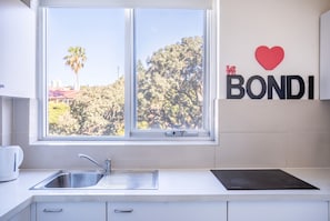 A kitchen with a window, a sink, and a wall-mounted sign that reads 'I LOVE BONDI'. - Bondi Beach Studio | 2 Min Walk to Beach, Sleeps 4, Work-From-Beach Desk (Bondi Beach)