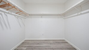 Un armadio con grucce di legno, un soffitto bianco e un pavimento in legno grigio.