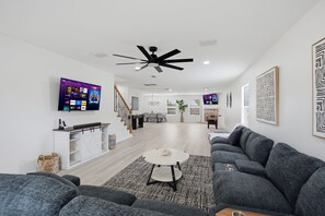 Un soggiorno moderno con un divano grigio, un tavolino da caffè e una TV a parete.