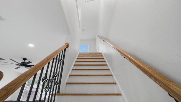 Una scala con ringhiere in legno e un lampadario geometrico nella parte superiore.