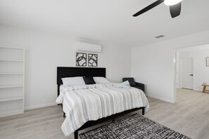 A bedroom with a bed, a ceiling fan, an air conditioning unit, and a patterned rug. - New Luxury & Spacious 5BR/3BA Retreat–Sleeps 16 – Prime location & Fully Stocked (McKinney)