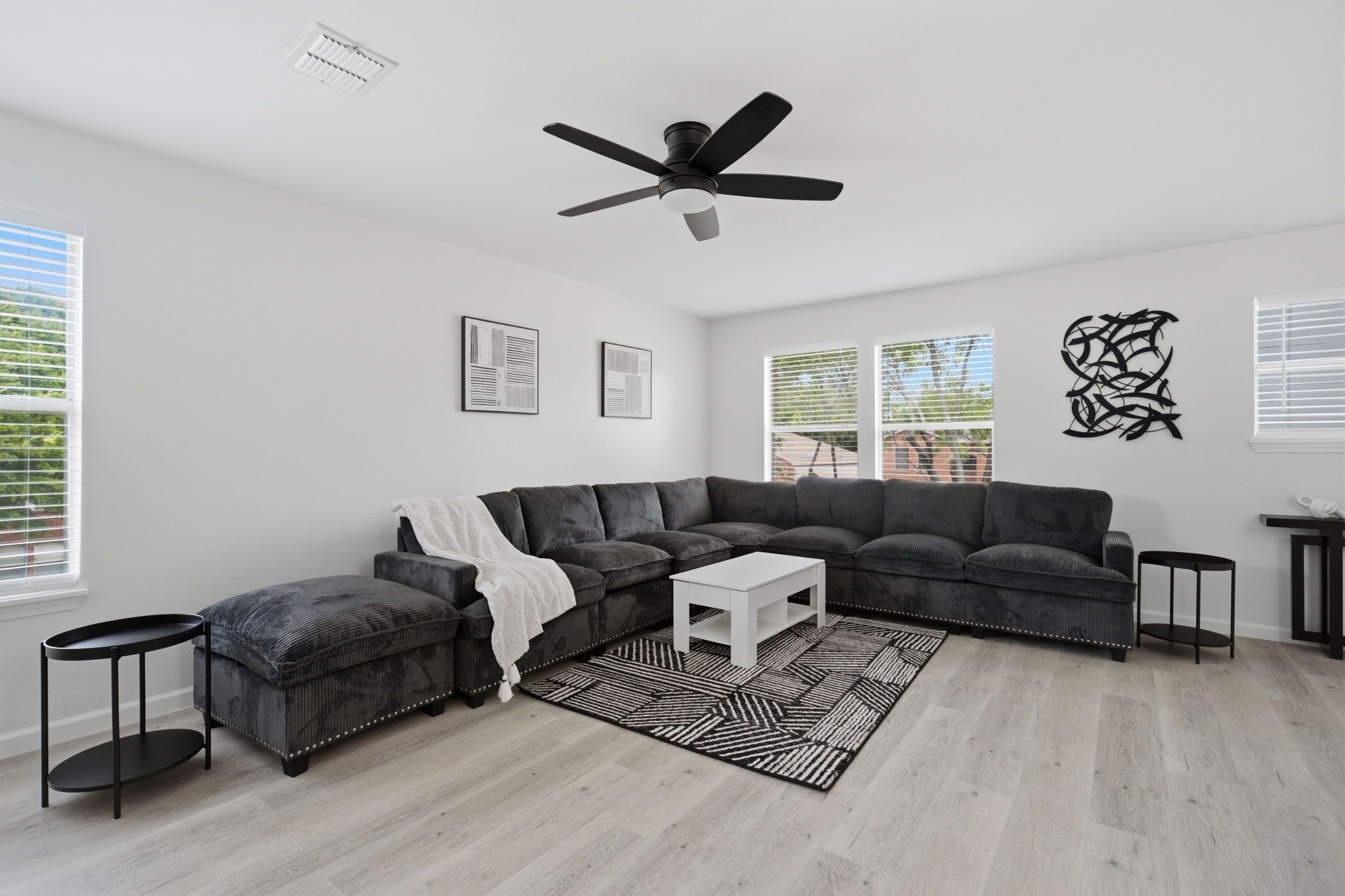 A modern living room with a sectional sofa, a white coffee table, and a patterned rug.