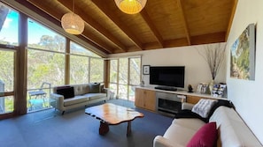 Un salon spacieux avec une grande télévision, un canapé, une table basse et une cheminée.
