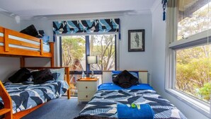 A bedroom with two beds, a window, a lamp, and a framed picture on the wall.