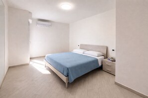 A bedroom with a bed, bedside table, and a wall-mounted air conditioner. - Lungomare del Cavo  Sea Just Steps Away (Rio Marina)