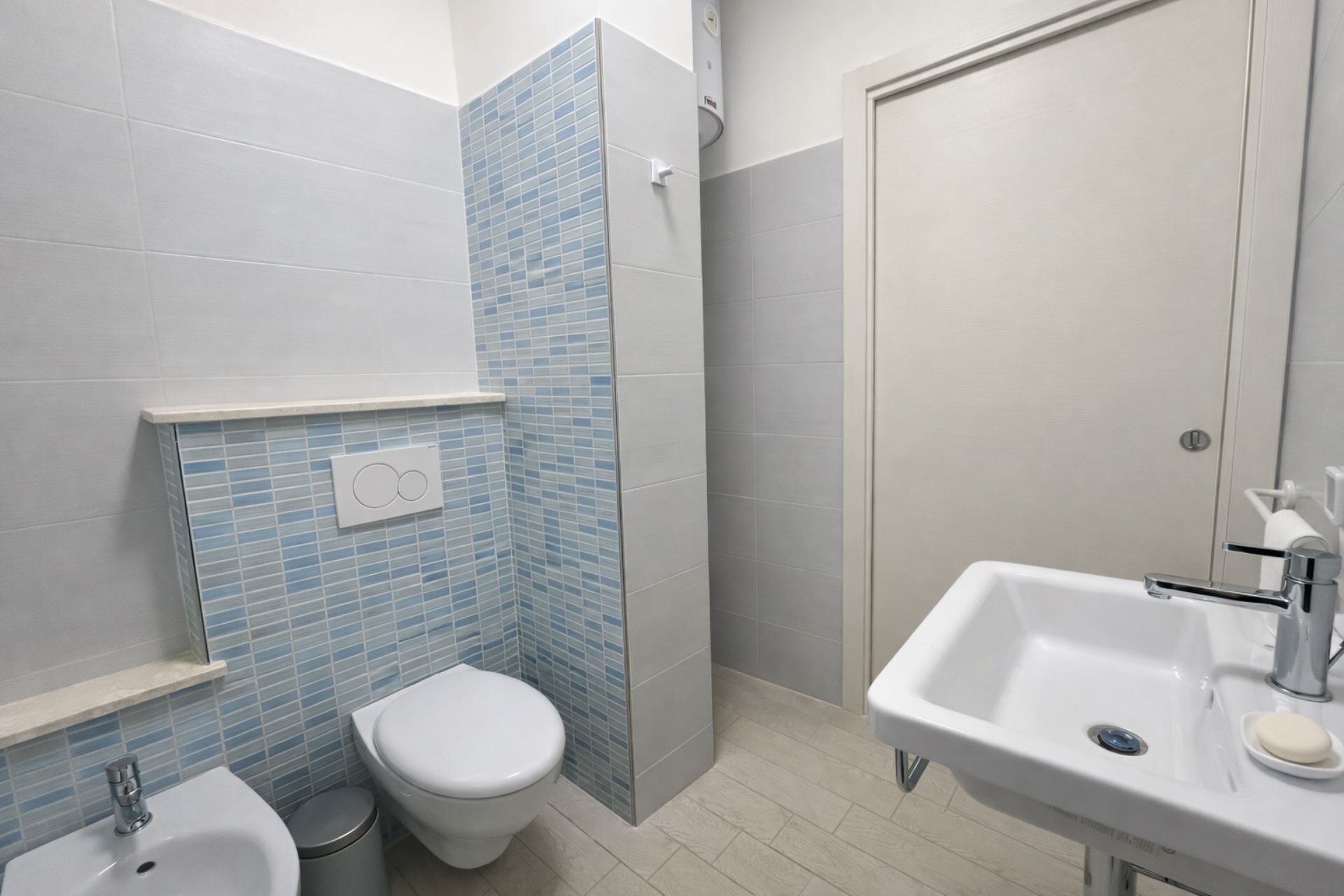 A bathroom with a toilet, bidet, sink, and a shower area.