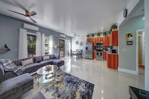 A modern living room with a sofa, coffee table, and a view into the kitchen area. - Glamorous 2Bed/2Bath/2K- 5★ DT Location-♛Hot Tub (Fort Lauderdale)