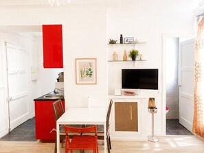 A compact living space with a kitchen, dining area, and a TV. - Le Valéry - Calme sur cour -Paris 16 (Paris)