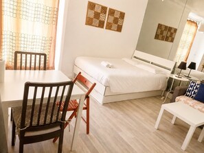 A hotel room with a bed, a desk, a chair, a small table, and a lamp. - Le Valéry - Calme sur cour -Paris 16 (Paris)