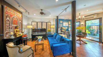 A living room with a blue sofa, a piano, a Buddha statue, and a decorative wall.