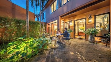 Un espacio de patio al aire libre con suelo de piedra, plantas en macetas y un conjunto de asientos.