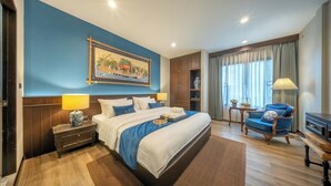 A hotel room with a large bed, a nightstand, a chair, a desk, and a window with curtains. - Aphirom Hometel (Bangkok)