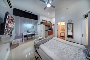 Une chambre moderne avec un lit, une table de chevet et une vue sur la cuisine.