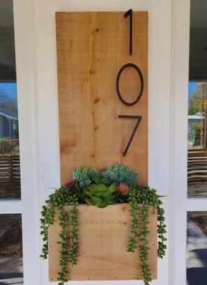 A wooden number plaque with the numbers 107, mounted on a white door. - Cozy Home 10 minutes to Riverwalk and Downtown (San Antonio)
