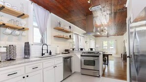 Una cucina moderna con mobili bianchi, elettrodomestici in acciaio inossidabile e mensole in legno.