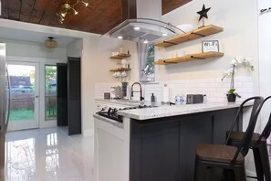 A modern kitchen with a central island, built-in appliances, and wooden shelves. - Cozy Home 10 minutes to Riverwalk and Downtown (San Antonio)