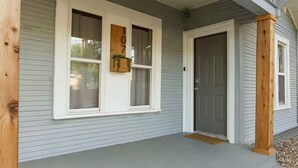 Una casa con un portico, un'entrata e una finestra con un numero.