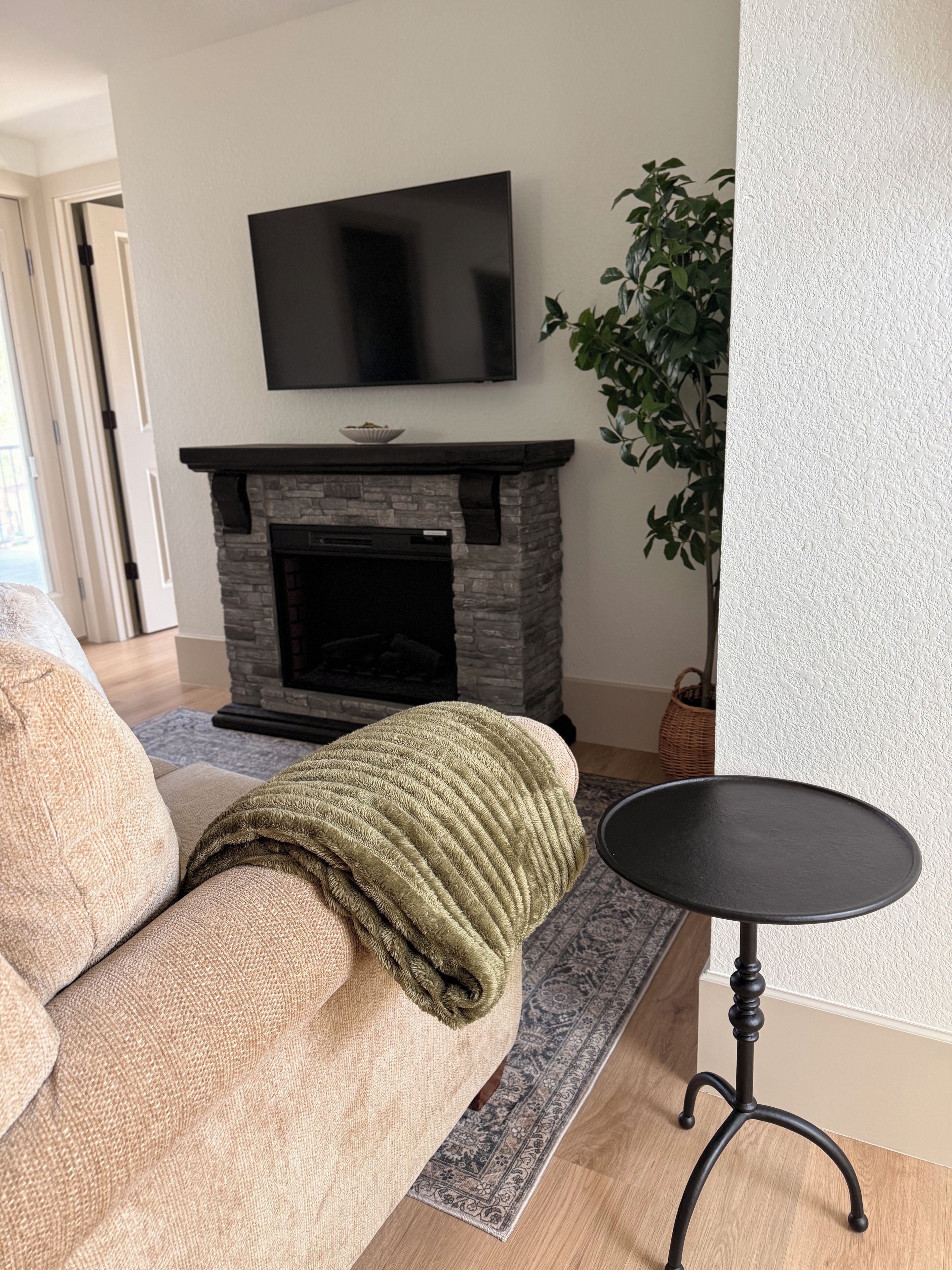 Un salon avec un canapé, une cheminée, un téléviseur et une petite table.