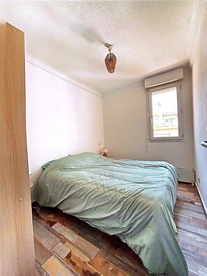 Una habitación pequeña con cama, ventana y puerta.