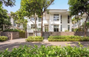 Ein modernes Mehrfamilienhaus mit geschlossenem Eingangstor, umgeben von üppiger Bepflanzung und einem gepflegten Rasen.