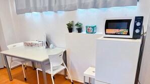 Un angolo cottura attrezzato con forno a microonde, un tavolo e sedie.