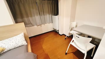 Una habitación pequeña y funcional con cama, escritorio y silla.