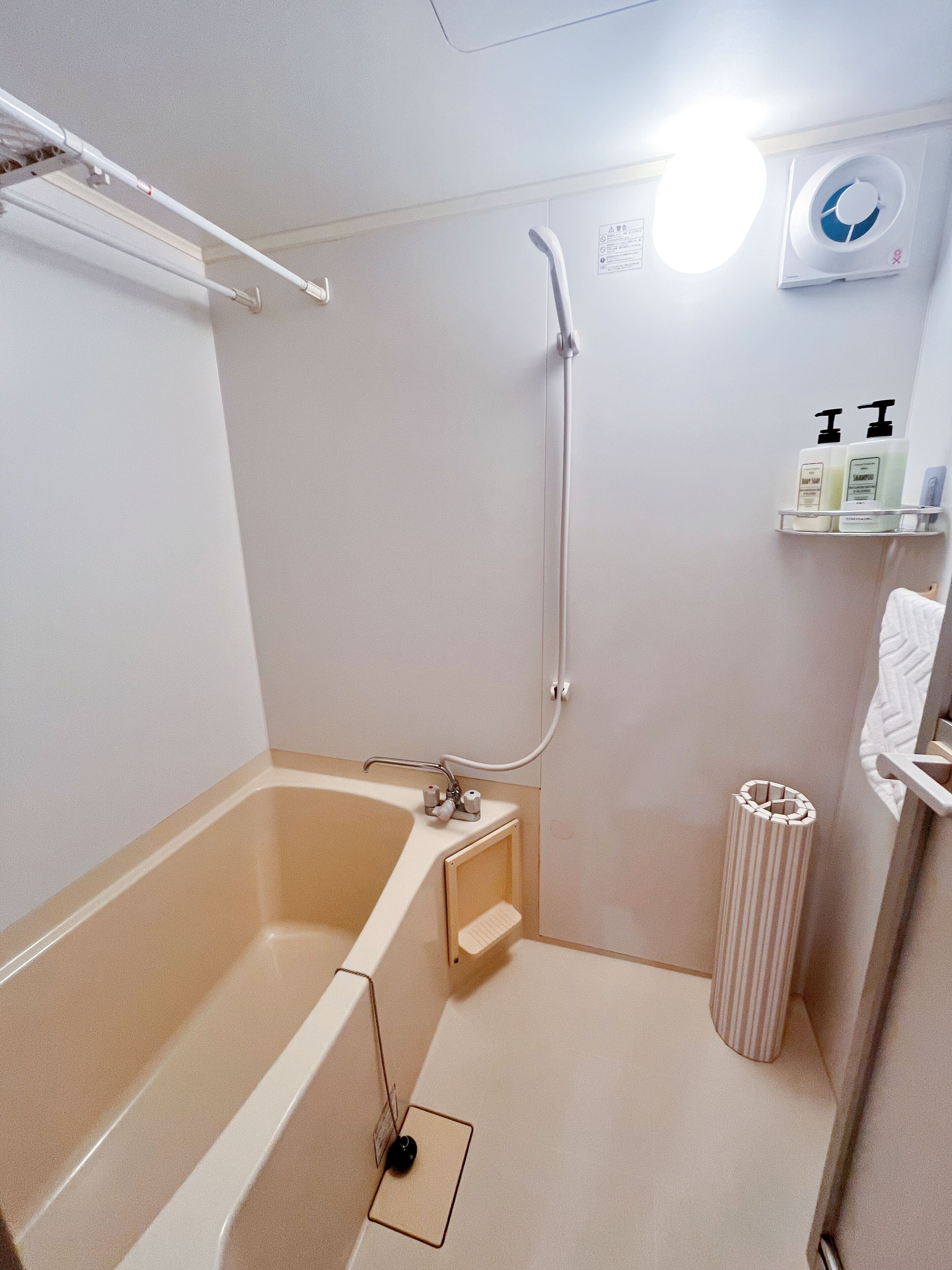 A bathroom with a bathtub, a shower, and a toilet. There are toiletries on a shelf.