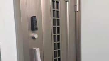 Puerta metálica de ascensor con teclado numérico, timbre y placa indicando el piso.
