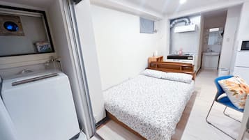Une pièce de taille modeste comprenant un lit, une petite kitchenette et une salle de bain.