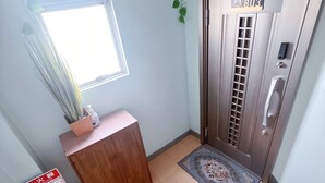 Una stanza con una scrivania in legno, un estintore, una finestra, una porta con una targa e una telecamera di sicurezza.